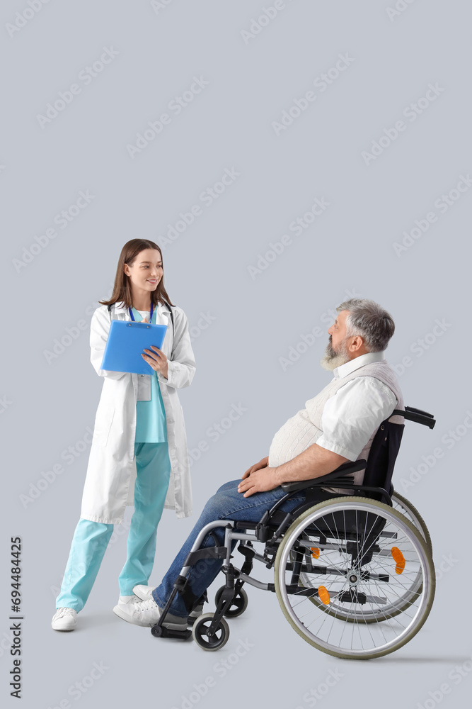Mature man in wheelchair and nurse with clipboard on light background Mature man in wheelchair and nurse with clipboard on light background