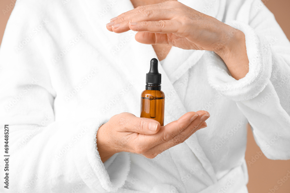 Mature woman with facial serum on brown background, closeup Mature woman with facial serum on brown background, closeup