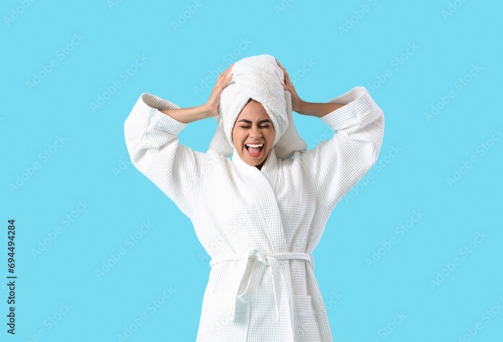 Young African-American woman in bathrobe after shower shouting on blue background Young African-American woman in bathrobe after shower shouting on blue background