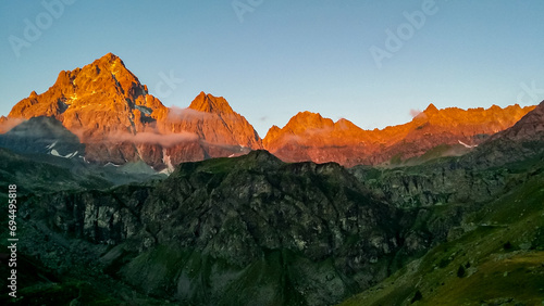 Scenic sunrise view of  mountain summit Monte Viso (Monviso) in the Cottian Alps, Piemonte, Italy, Europe. The rock walls of the Stone king are shining in warm red orange colors. Majestic landscape photo