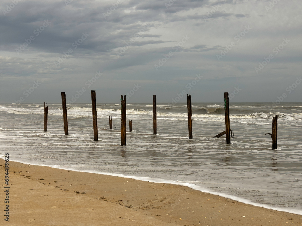 Stark wooden pilings, age unknown, are all that remain of a building subject to years of heavy weather along a shoreline in Marineland, Florida, for motifs of location, climate and the environment