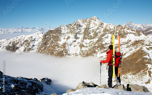 A captivating image of an adventurer in the midst of a ski expedition on a breathtakingly beautiful mountain. The adventurer is fully equipped, holding skis and poles.