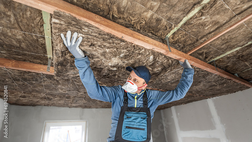 Ceiling insulation. The Worker putting a thermal insulation from glass wool. photo