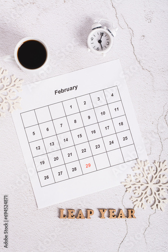 Leap year concept, calendar, coffee, alarm clock and text on light top and vertical view