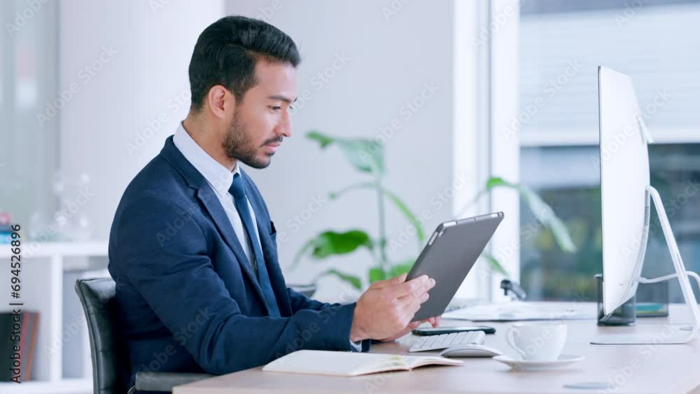 Business analyst comparing statistics on a digital tablet while researching financial strategies on a desktop. Professional man checking data while using technology to plan a savings budget Business analyst comparing statistics on a digital tablet while researching financial strategies on a desktop. Professional man checking data while using technology to plan a savings budget