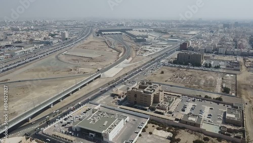 Cars and Trucks driving down a motorway in Saudi Arabia with a massive train station in the background. Jeddah's Transportation Hub.