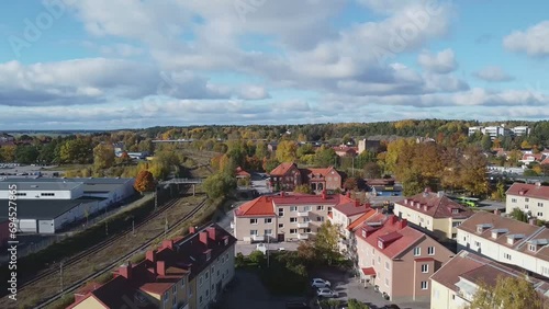 Following train tracks at low altitude towards a cozy old train station covered in red vines during a sunny autumn day