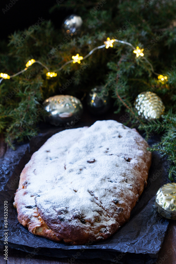 Christmas stollen with dried fruits, nuts and spices, Christmas decorations on a dark wooden background. Rustic style.
