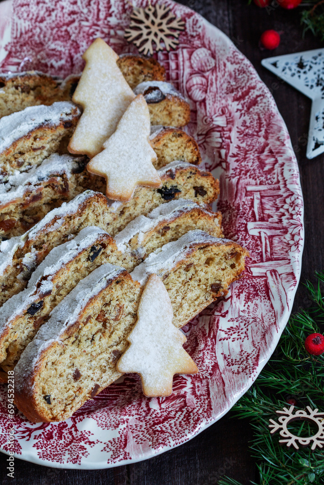 Christmas stollen with dried fruits, nuts and spices, Christmas decorations on a dark wooden background. Rustic style.