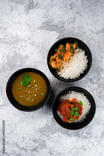 Set of Asian food: rice with stew and vegetables and lentil soup puree in a bowls.
