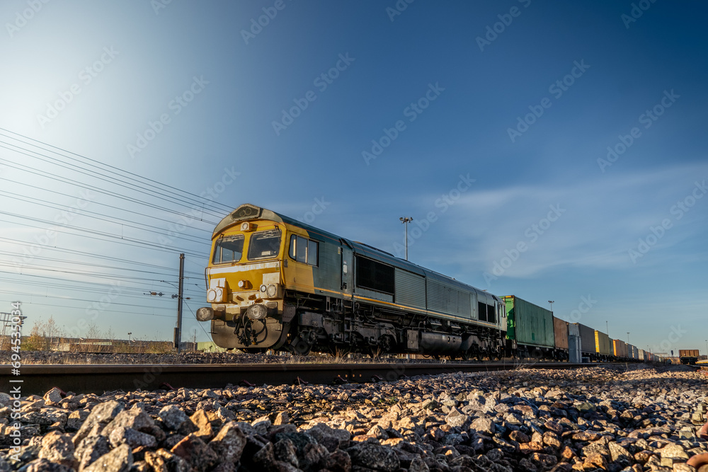 A UK freight train with locomotive and wagons transporting shipping container boxes - obrazy, fototapety, plakaty 