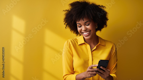Young woman smiling and holding her smartphone on a colored background