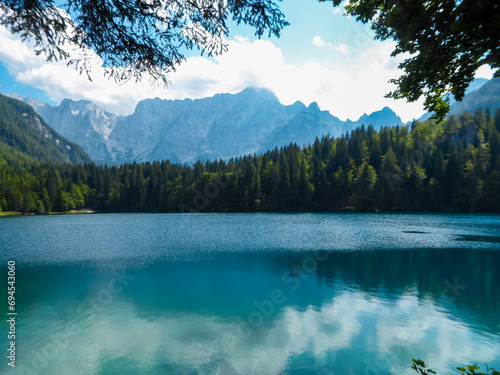 Scenic view of Superior Fusine Lake (Laghi di Fusine) in Tarvisio, Friuli-Venezia Giulia, Italy, Europe. Mount Mangart and Julian mountain range reflection in green alpine lake. Nature and wilderness photo