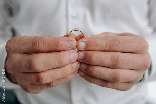 Close-up of male hands holding a wedding ring. the groom holds a diamond wedding ring with two fingers.