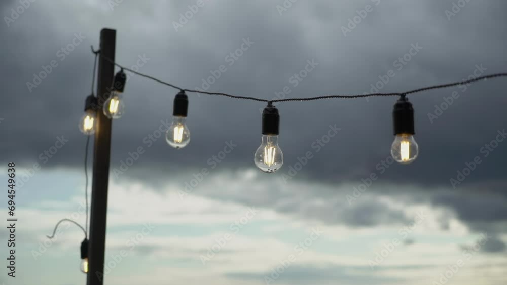 String light garland with white lamp bulbs. Preparation for holiday party in summer. Wedding or birthday decoration. String light garland with white lamp bulbs. Preparation for holiday party in summer. Wedding or birthday decoration.