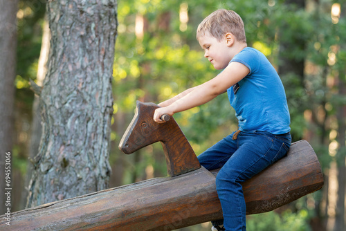 Happy cute little boy lift up with Outdoor seesaw or wooden swing on a playground photo