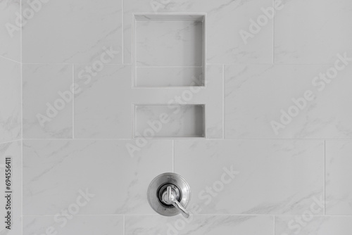 Close-Up of Shower Niche Built into Luxurious White Marble Wall with Herringbone Pattern, Featuring a Silver Shower Handle photo