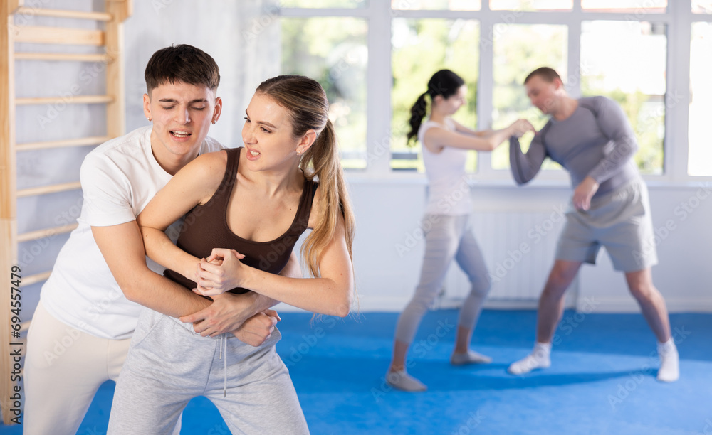 Young woman and young man practicing self-defense techniques in gym..