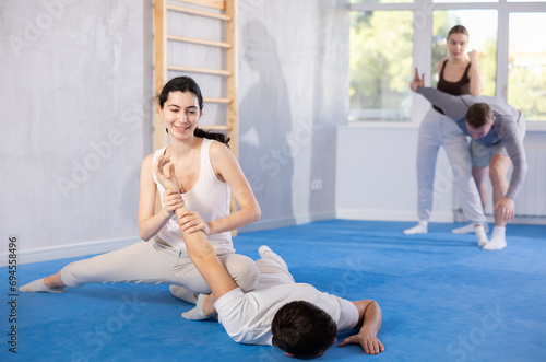 Sportive young woman practicing arm twist technique against her partner during self-defense courses