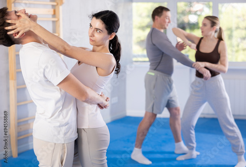 Aggressive young woman practicing self-defense techniques in pairs with guy during workout session © JackF