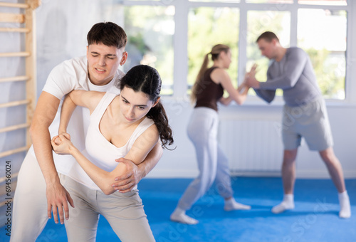 Aggressive young woman practicing self-defense techniques in pairs with guy during workout session © JackF