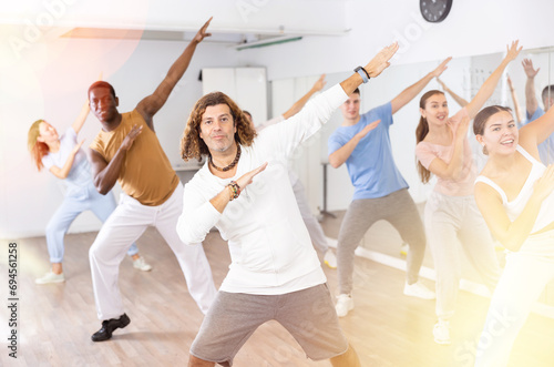 Group of positive dancers repeat dance in dance hall