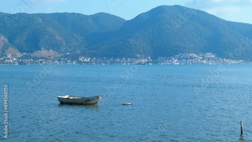 Empty boat against mountain hill. A view of empty fishing boat floating in the calm sea waves by tropical mountains in laggon under summer sun. photo