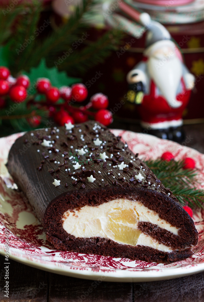 Chocolate roll stuffed with butter cream and pineapple on a Christmas background. Rustic style.
