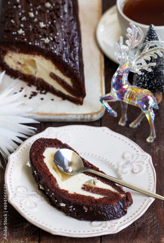 Chocolate roll stuffed with butter cream and pineapple on a Christmas background. Rustic style.
