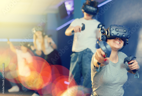 Young woman with handheld controllers in hands clearly excited and engaged in virtual world experiencing through VR glasses covering face. Concept of immersion and interactivity in game