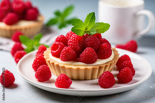Vanilla tartlets with raspberries and mints on light background