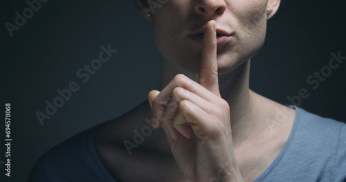 Woman gesturing to be quiet with a finger before her mouth.