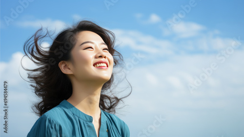 A Asian woman breathes calmly looking up isolated on clear blue sky