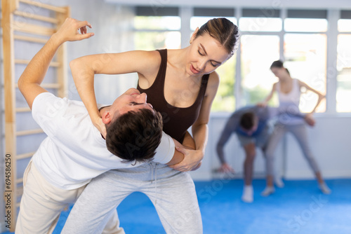 Woman practices blows to the head of a male attacker during self-defense training.