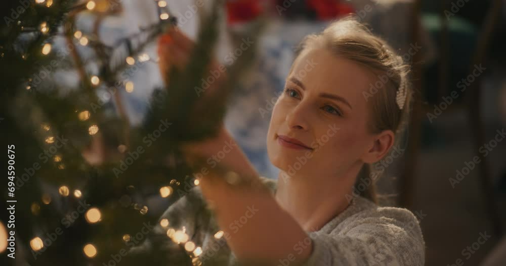 Young woman adjusting glowing led lights on tree Young woman adjusting glowing led lights on tree
