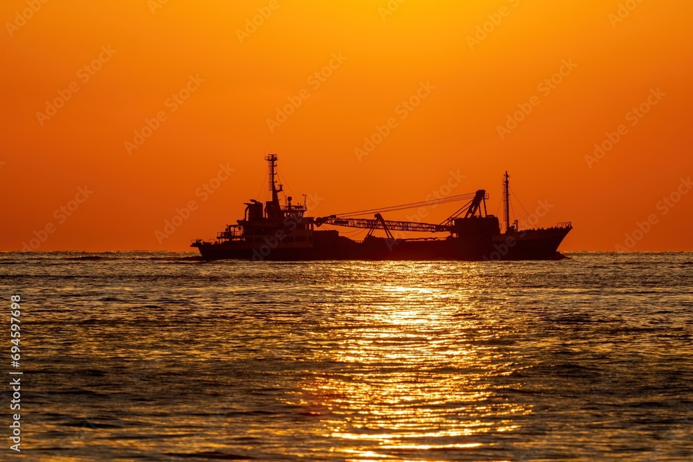 夕日を浴びながらサンロードの上を進む貨物船の情景 夕日を浴びながらサンロードの上を進む貨物船の情景