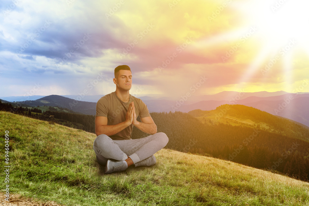 Man meditating in mountains at sunrise, space for text