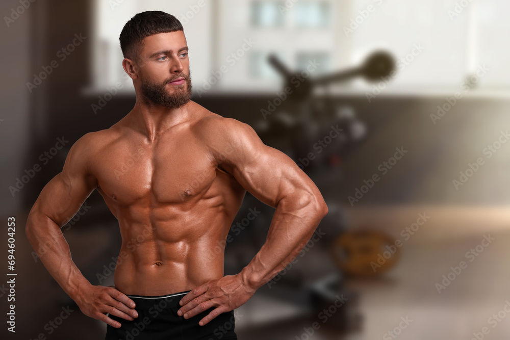 Obraz premium Handsome bodybuilder with muscular body in gym, space for text