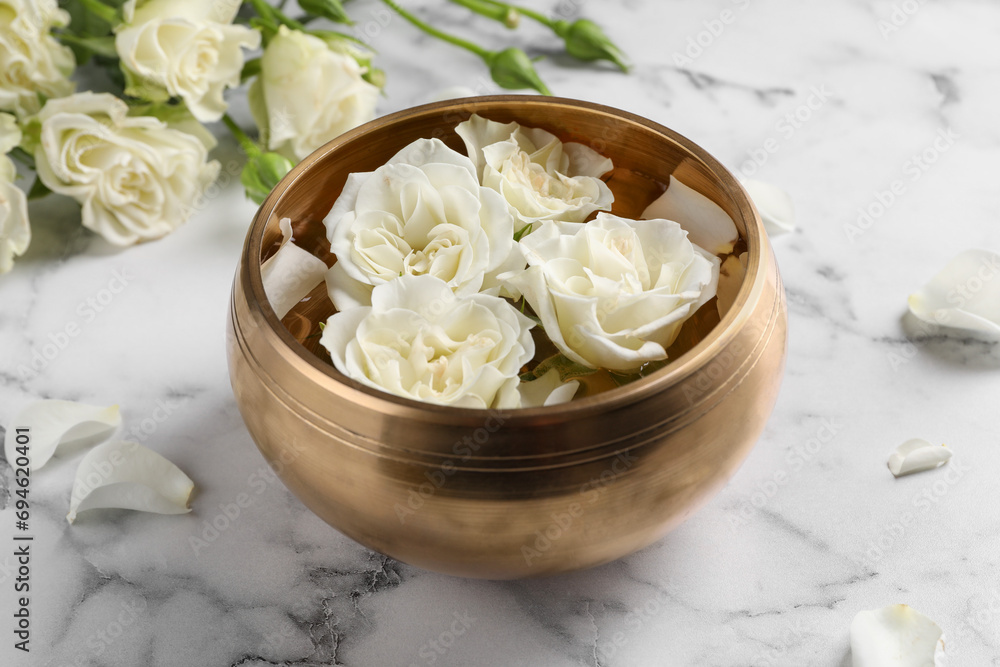Tibetan singing bowl with water and beautiful roses on white marble table, closeup Tibetan singing bowl with water and beautiful roses on white marble table, closeup