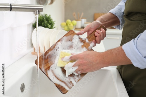Foto Man washing wooden cutting board in kitchen sink, closeup