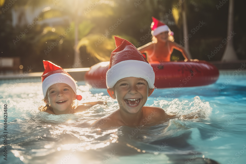 Little kids in a Santa hat and swimming around in the pool, the concept of celebrating Christmas and new year in tropical countries - obrazy, fototapety, plakaty 