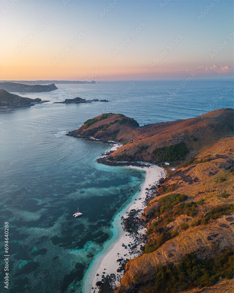Aerial view of the coast of southern Lombok. A catamaran down at sea. Sunset. Indonesia