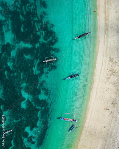 Bird's-eye view. Half blue sea and half beach. Fishing boats at sea. Sky blue color. Sunny day. Lombok. Indonesia © Agata