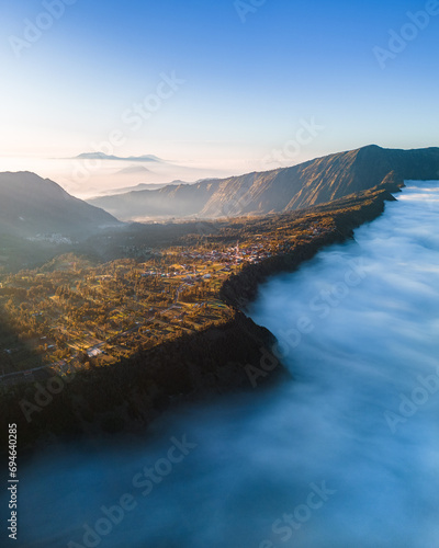 Drone photo of the town of Cemorolawang near the Bromo volcano. Clouds under the city. Bromo sunrise. Indonesia.
