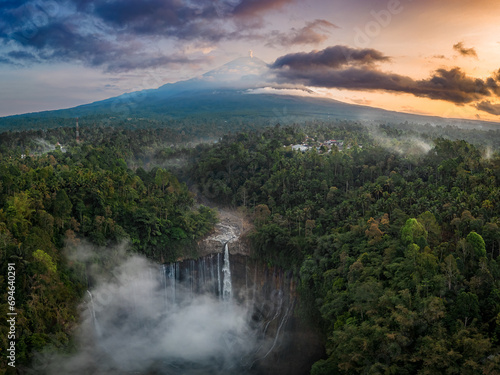 Aerial view of Tumpak Sewu Waterfall and Mount Semeru at sunrise located in East Java, Lumajang, Indonesia. Natural landscape background.