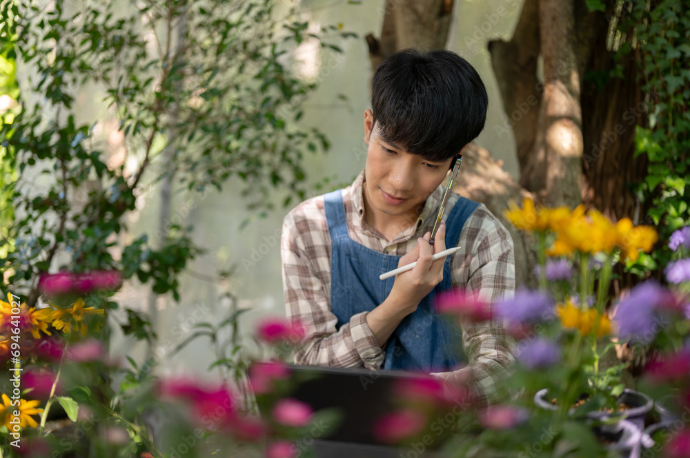 An Asian man small flower shop owner is talking on the phone with his client in his flower garden. An Asian man small flower shop owner is talking on the phone with his client in his flower garden.
