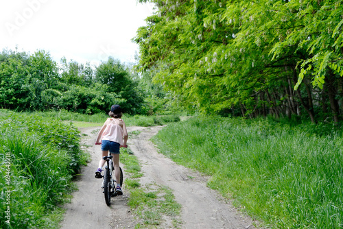Young girl cyclist enjoy the beautiful sunrise on summer forest trail © Luci