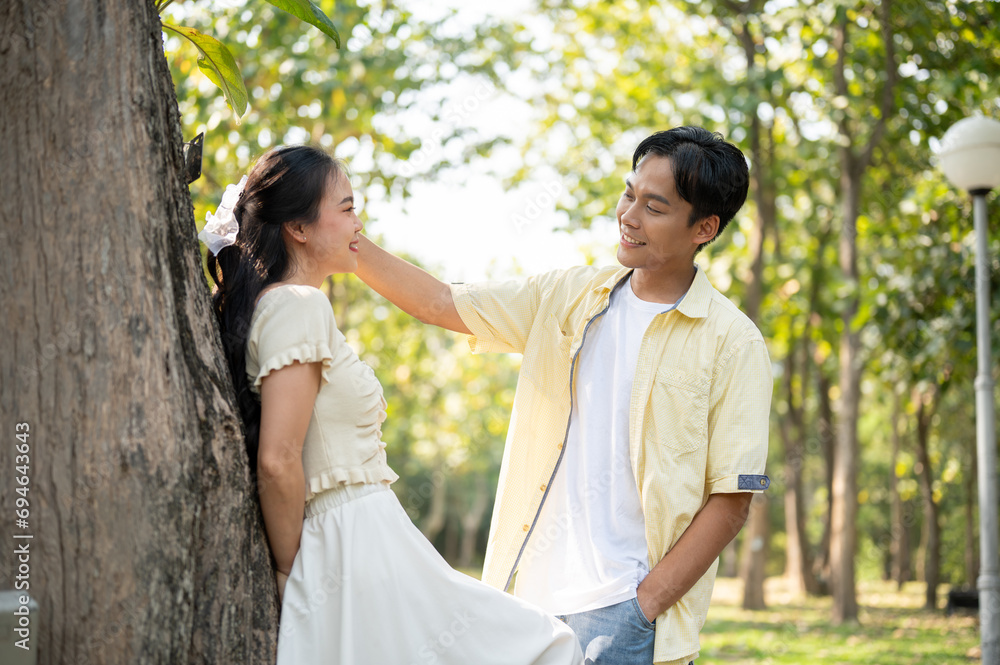 A lovely young Asian couple is flirting in a green park on a bright day. boyfriend and girlfriend A lovely young Asian couple is flirting in a green park on a bright day. boyfriend and girlfriend