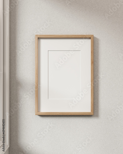 A minimalist wood picture frame mockup hanging on a white wall in a modern Scandinavian room.