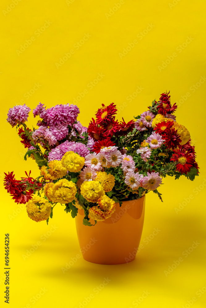 Still life with a bouquet of chrysanthemums in a yellow vase on a yellow background